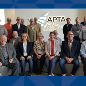 A group of men and women faculty in front of an APTA banner