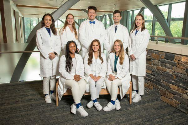 A group of eight students all dressed in white