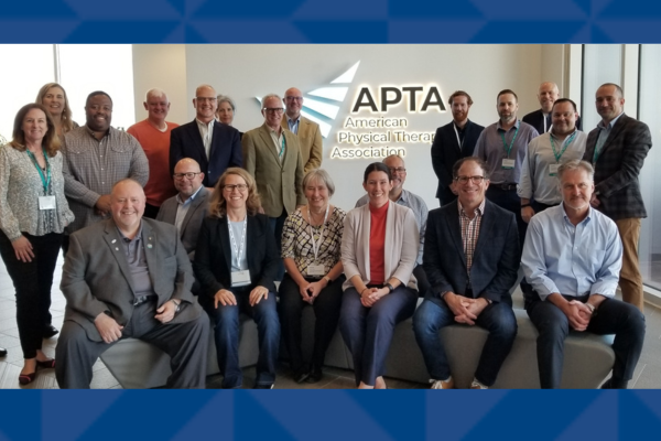 A group of men and women faculty in front of an APTA banner