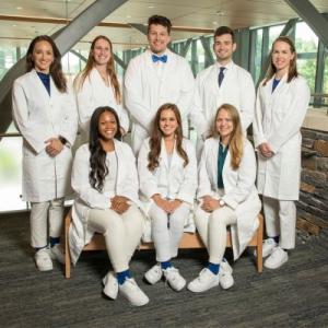 A group of eight students all dressed in white